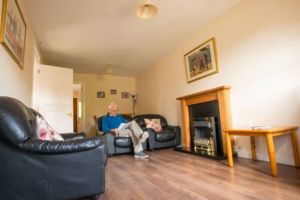 Ein Wohnzimmer mit Kamin, Ledersofas und einem Holztisch.