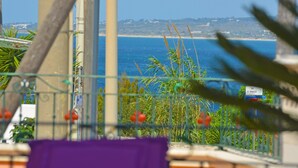 Un balcon avec vue sur la mer et sur le paysage urbain au loin.