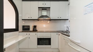 A compact kitchen with white cabinets, a microwave, a coffee maker, and a dishwasher.