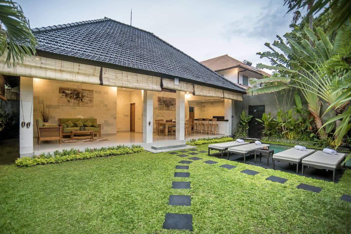 A modern house with a covered patio, a lawn, and outdoor seating.