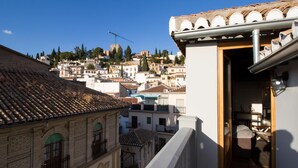 A view of a residential area with terracotta-tiled roofs, a balcony with a wooden door, and a clear blue sky. - Fantastic penthouse with terrace and views (Granada)