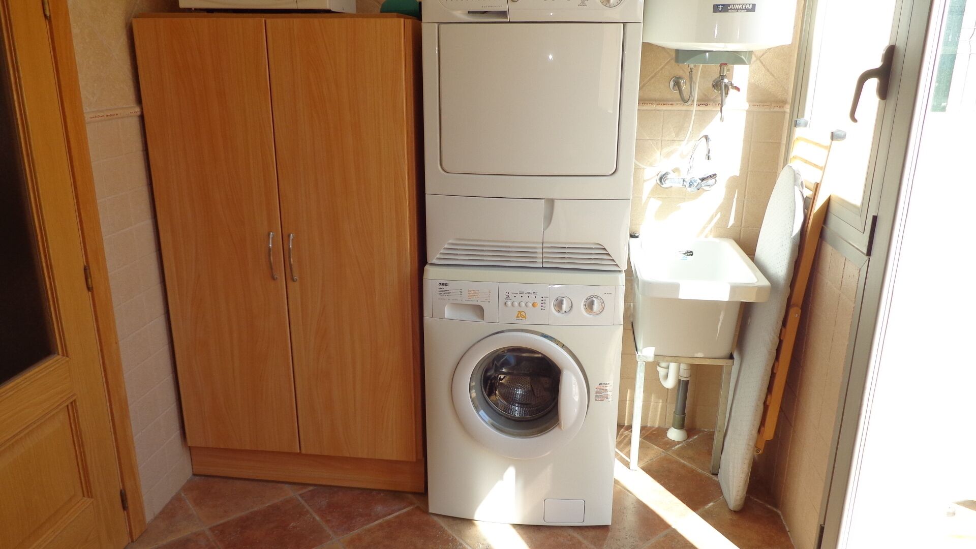 Une petite buanderie équipée d’un lave-linge à chargement frontal, d’un sèche-linge et d’un évier.