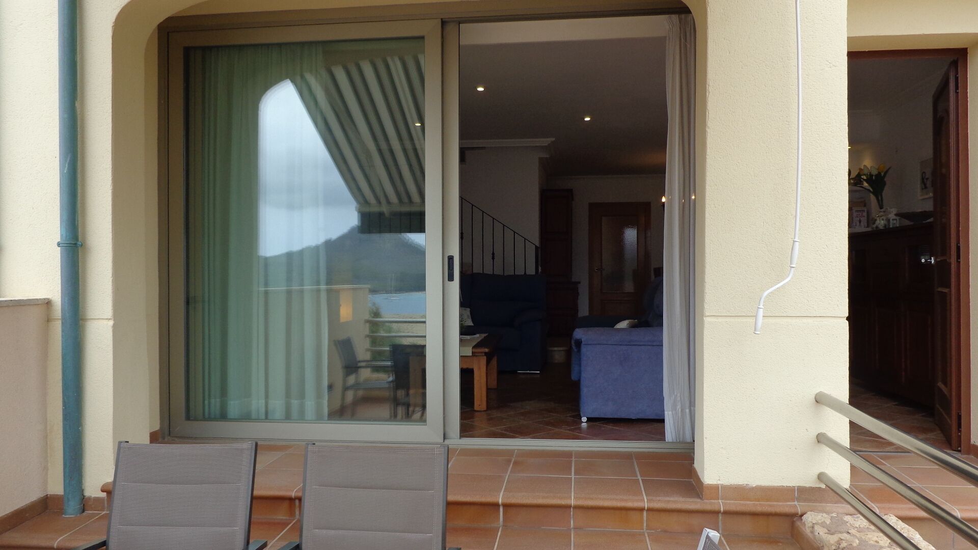 A sliding glass door leading to a living area with a sofa and a dining table.