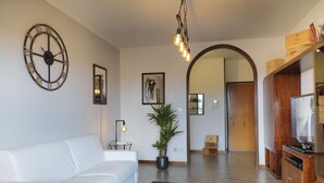 A modern living room with a white sofa, a round wall clock, and a potted plant. - Bellaria Park "Hills View" Residences (san lazzaro di savena (Bologna))