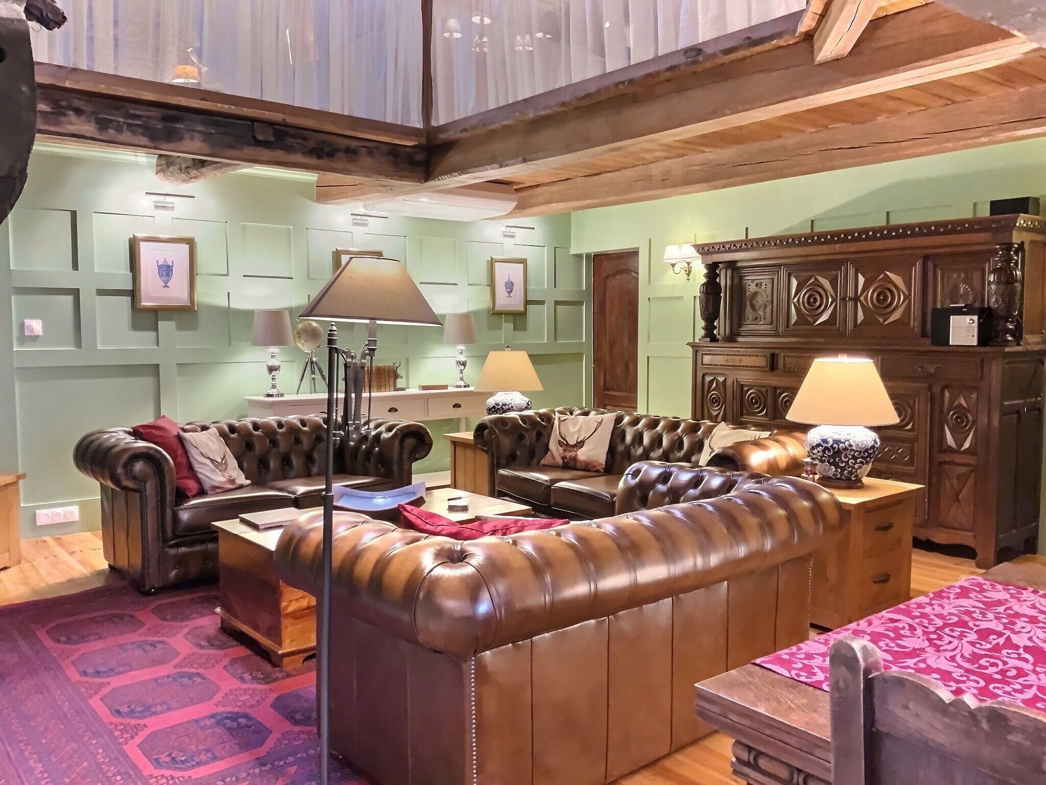 Une pièce comprenant un ensemble de canapés en cuir marron, un meuble en bois agrémenté d’éléments décoratifs et un tapis à motifs.