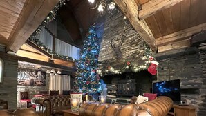 Un salon chaleureux avec un canapé en cuir, un sapin de Noël et une cheminée en pierre.