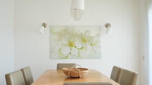 Et spiseområde med et træbord, fire stole, en vævet kurv og en vægmonteret lampe.
