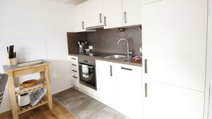 A modern kitchen with white cabinets, a stainless steel sink, and a built-in oven. - Nice apartment for 4 guests with WIFI, TV and balcony (Pians)
