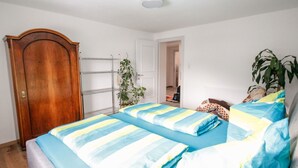 A bedroom with two beds, a wooden door, a metal shelf unit, and a potted plant. - Nice apartment for 4 guests with WIFI, TV and balcony (Pians)