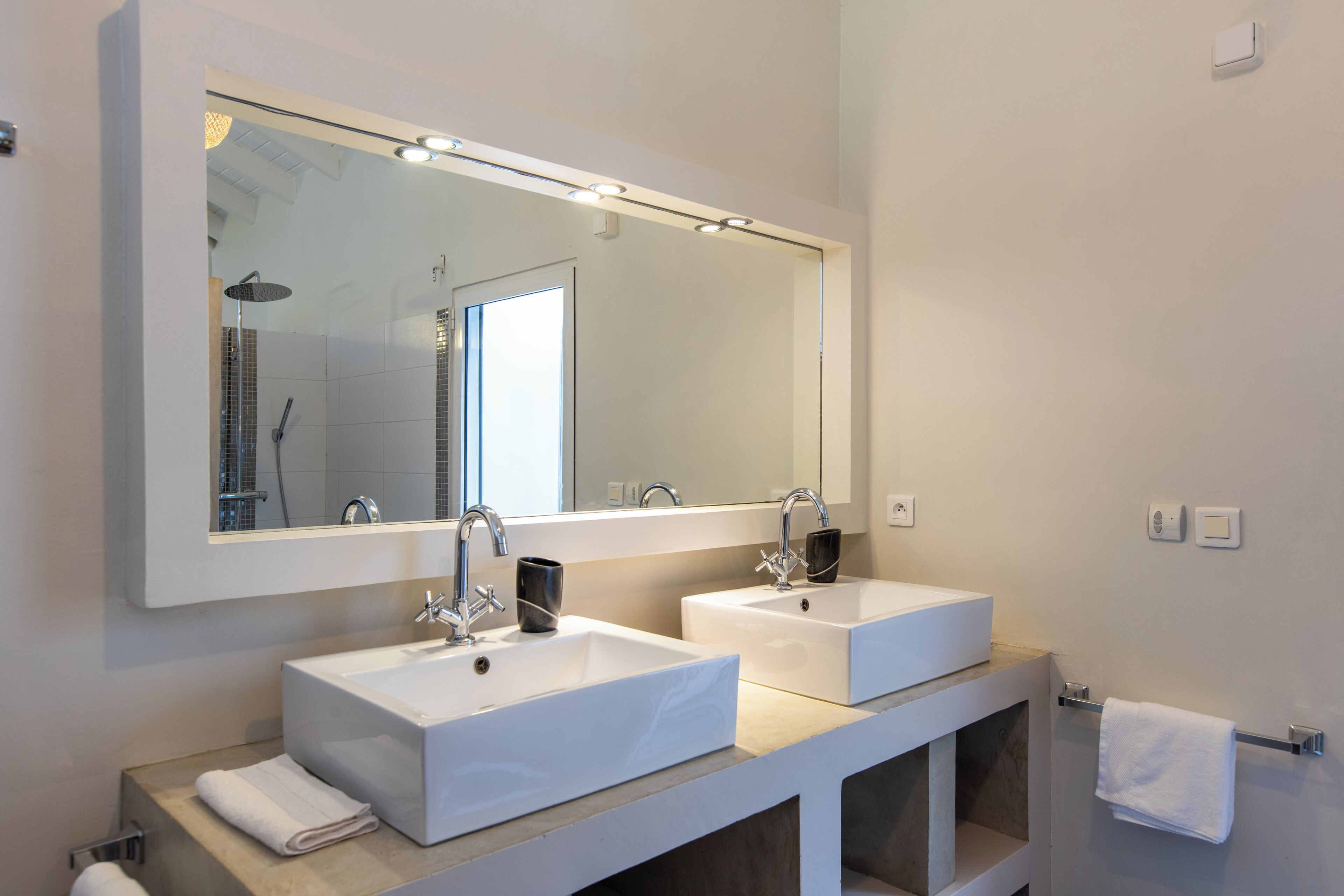 Un bagno moderno con due lavabi bianchi, un ampio specchio e un porta asciugamani.