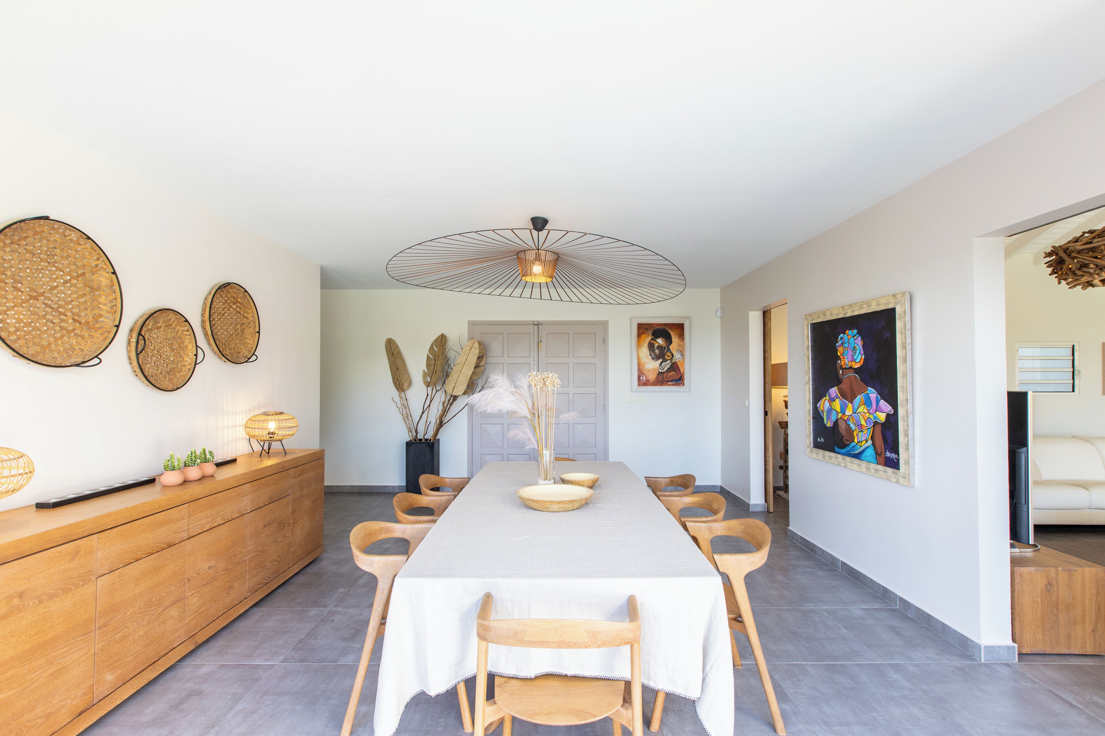 A spacious dining area with a long table, wooden chairs, and a modern pendant light.
