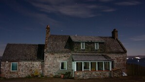 A stone house with a sloped roof, a chimney, and a small porch with a bench. - Uninterrupted sea views across the Moray Firth home to dolphins (Rosemarkie)