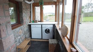 A compact laundry room with a washing machine, dryer, and a small shelf with laundry supplies. - Uninterrupted sea views across the Moray Firth home to dolphins (Rosemarkie)