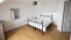 A bedroom with a bed, a mirror, a ceiling light, and a door. - Uninterrupted sea views across the Moray Firth home to dolphins (Rosemarkie)