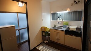 A compact kitchen with a refrigerator, sink, and a window with a view. - JQ Villa Kyoto Higashikujo (Kyoto)