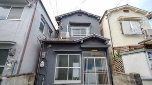 A residential building with a grey facade, a small balcony, and a visible air conditioning unit. - JQ Villa Kyoto Higashikujo (Kyoto)