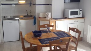 A compact kitchen with white cabinets, a microwave, and a small refrigerator.