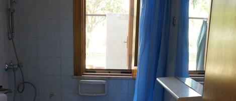 A small bathroom with two toilets, a sink, and a shower.