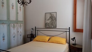 Une chambre à coucher comprenant un lit, une table de chevet, une lampe, un miroir et un tableau accroché au mur.