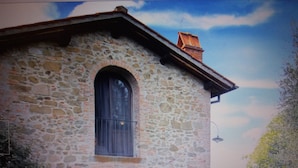 Ein Steinhaus mit einem großen Bogenfenster und einer Holztür.