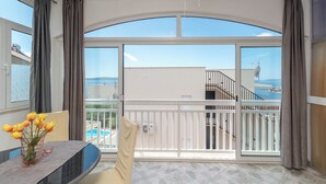 A balcony with a view of the sea and buildings, a glass table with a vase of flowers, and a chair. - TIA 1 with one bedroom and sea view, in Okrug Gornji (Okrug Gornji)