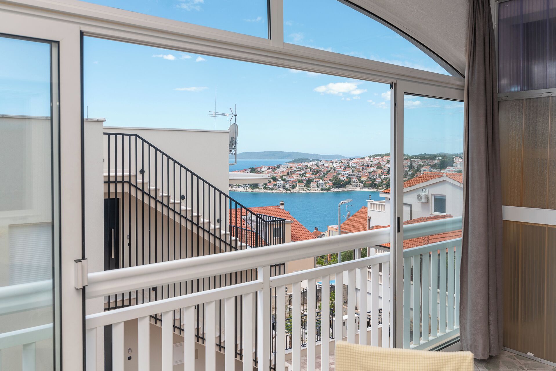 A balcony with a view of a coastal town and a body of water.