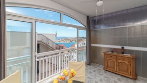 A balcony with a view of a coastal town, a ceiling fan, and a wooden cabinet. - TIA 1 with one bedroom and sea view, in Okrug Gornji (Okrug Gornji)