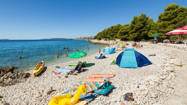 A beach with clear blue water, people swimming, and tents set up. - TIA 1 with one bedroom and sea view, in Okrug Gornji (Okrug Gornji)