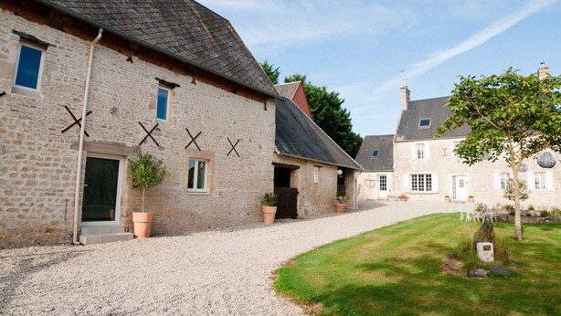 Un bâtiment en pierre avec une allée en gravier et une pelouse.