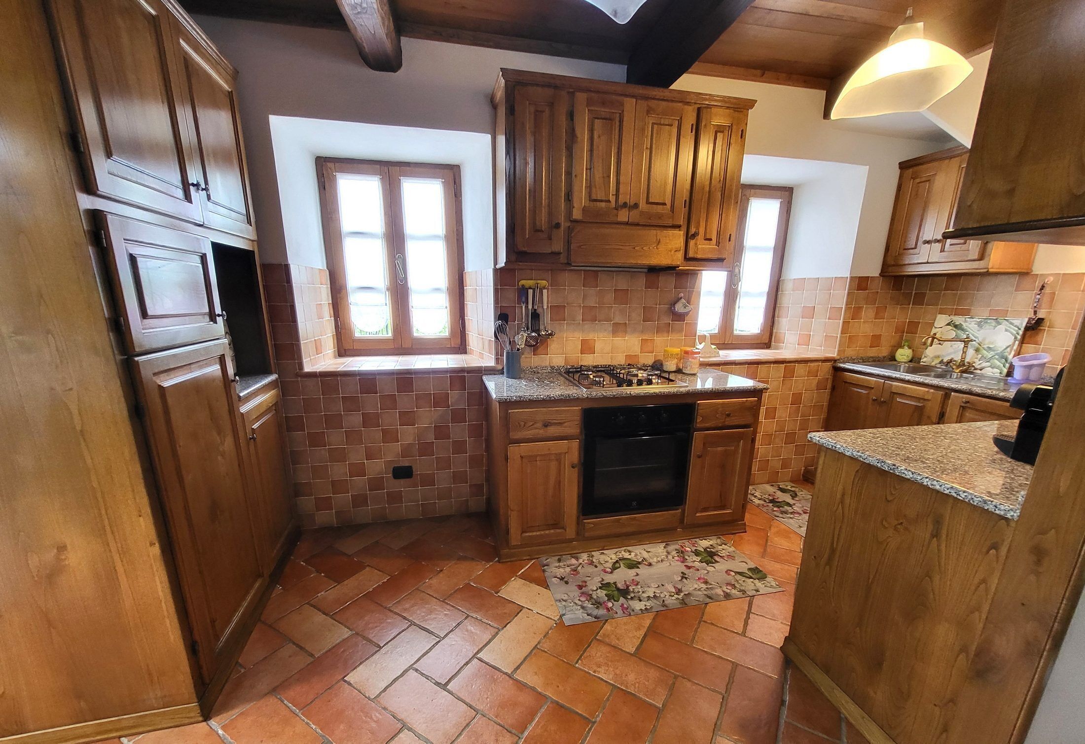 Uma cozinha com armários de madeira, painel de azulejos, fogão a gás e uma janela.