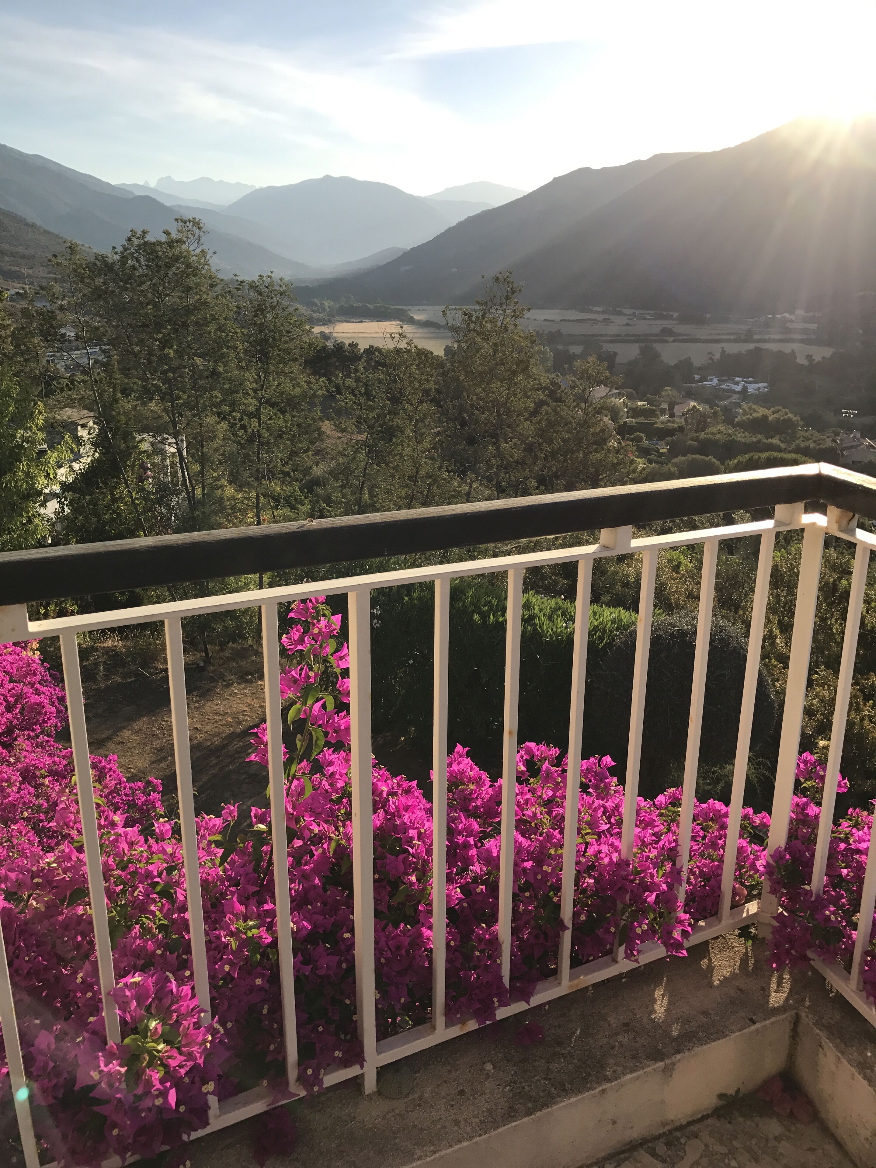 A balcony with a view of mountains and a valley.
