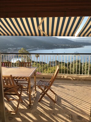 A wooden deck with a table and chairs, overlooking a bay with boats and a distant shoreline. - Family villa in Corsica with fabulous sea views (Vico)