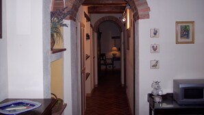 A narrow hallway with a brick archway, a dining area in the distance, and a microwave on a counter. - Tuscany. Lovely holiday home with swimming pool. (Castellina in Chianti)
