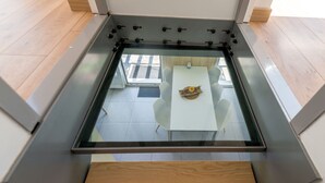 A modern room with a glass floor, white walls, and a wooden floor.