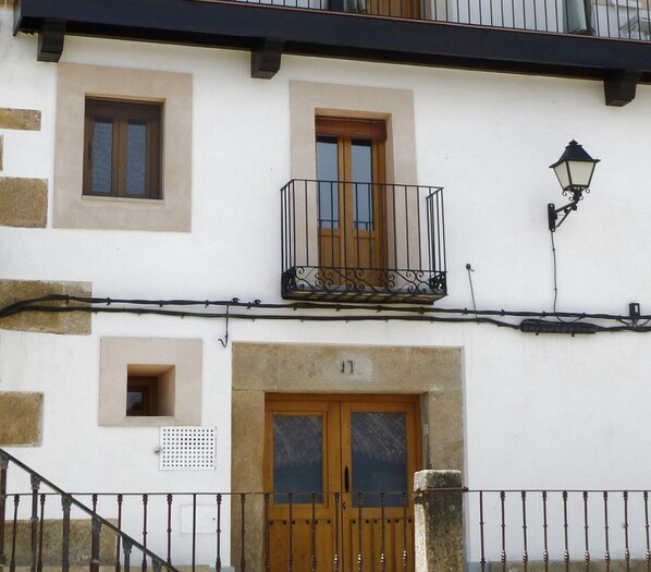 Un bâtiment doté d’un balcon, d’une porte et d’une petite fenêtre.