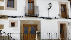 Un bâtiment à deux étages, doté de balcons, de portes en bois et d’un toit recouvert de tuiles.