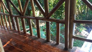 Eine Holzterrasse mit Geländer, die auf einen Garten blickt.