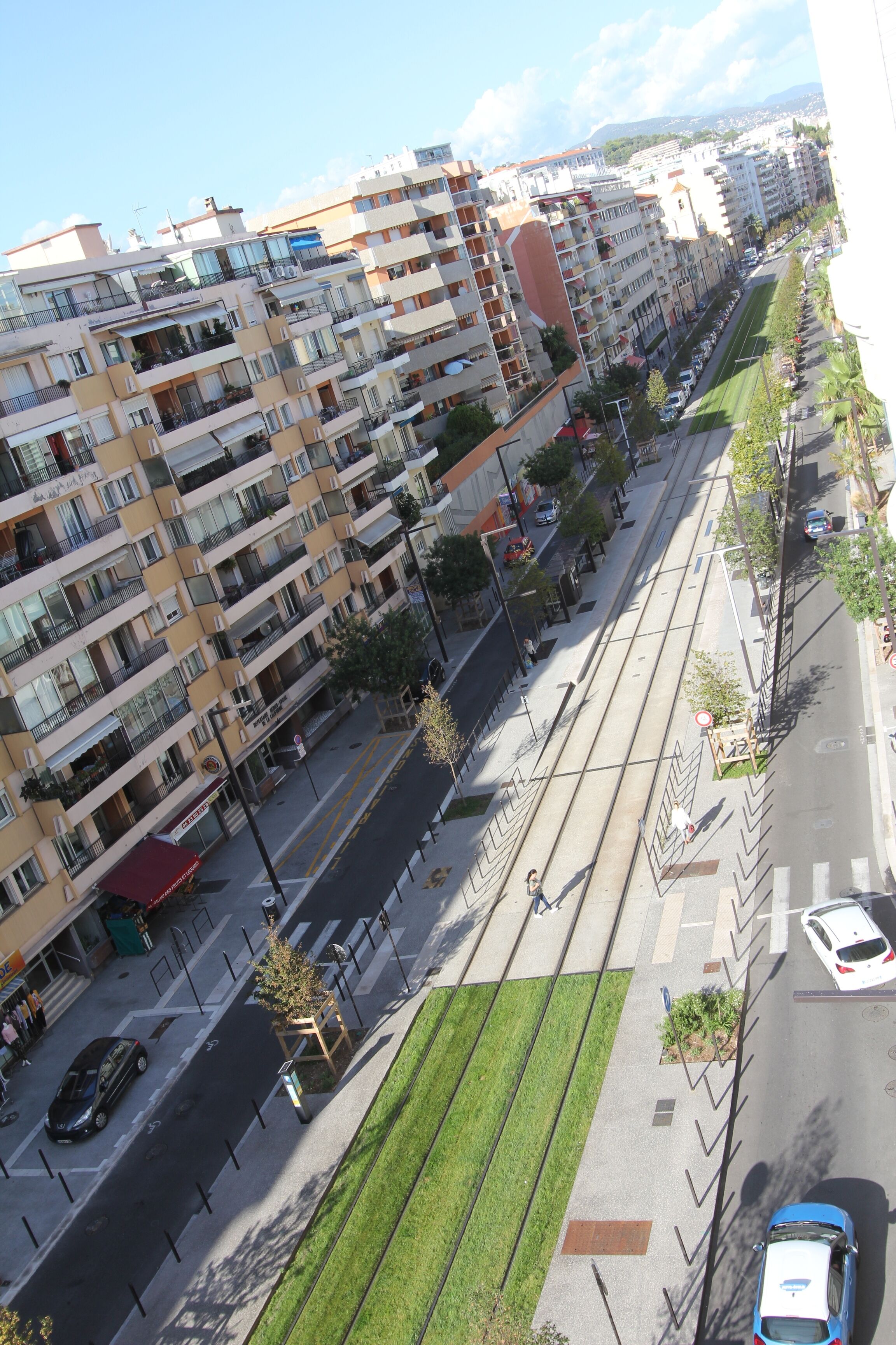 Ein mehrstöckiges Wohngebäude mit Balkonen, einer Straßenbahnhaltestelle und einem Fußweg.