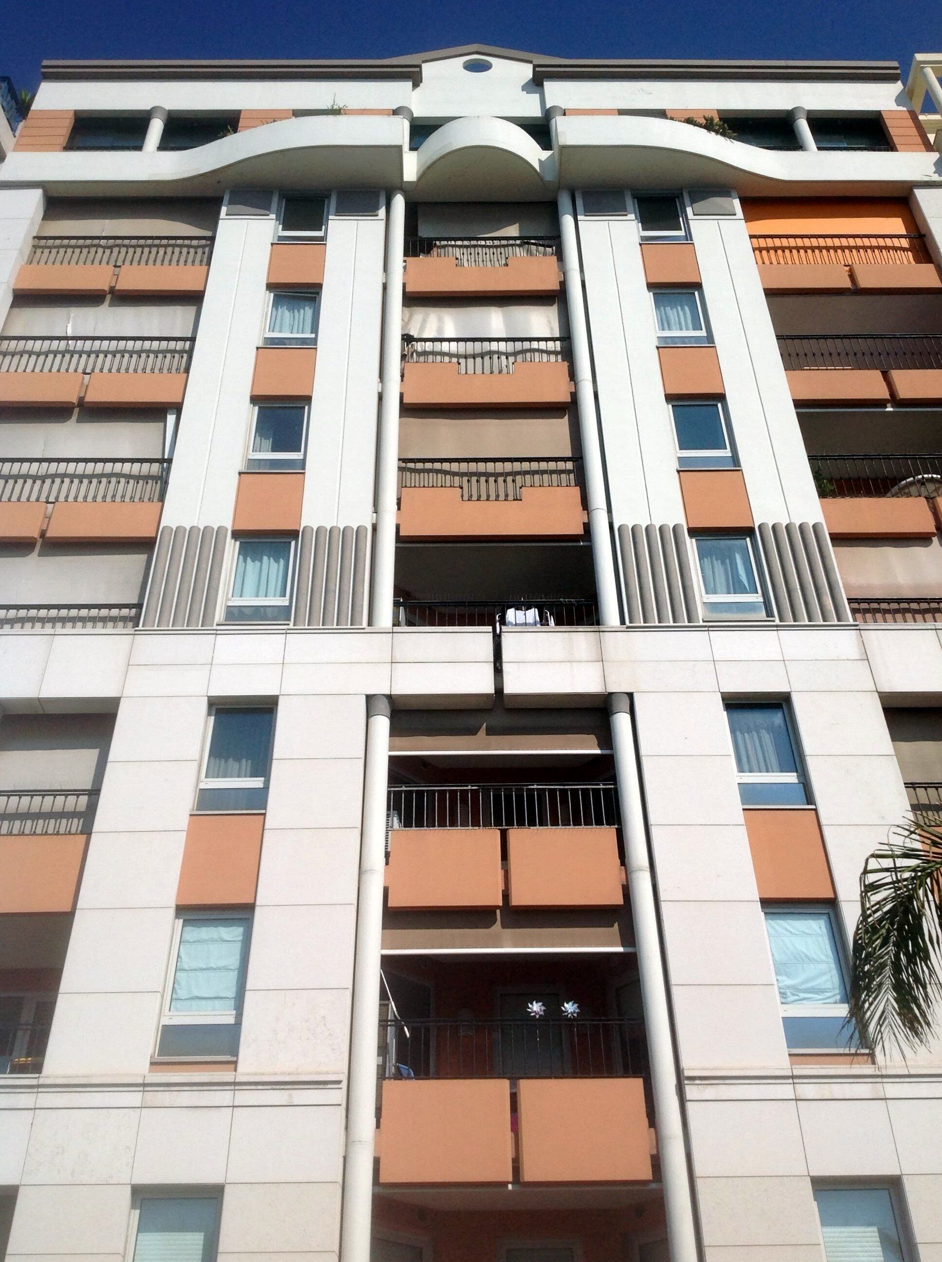 Un edificio de varios pisos con un atrio central, balcones en cada planta y una entrada destacada con un arco decorativo.