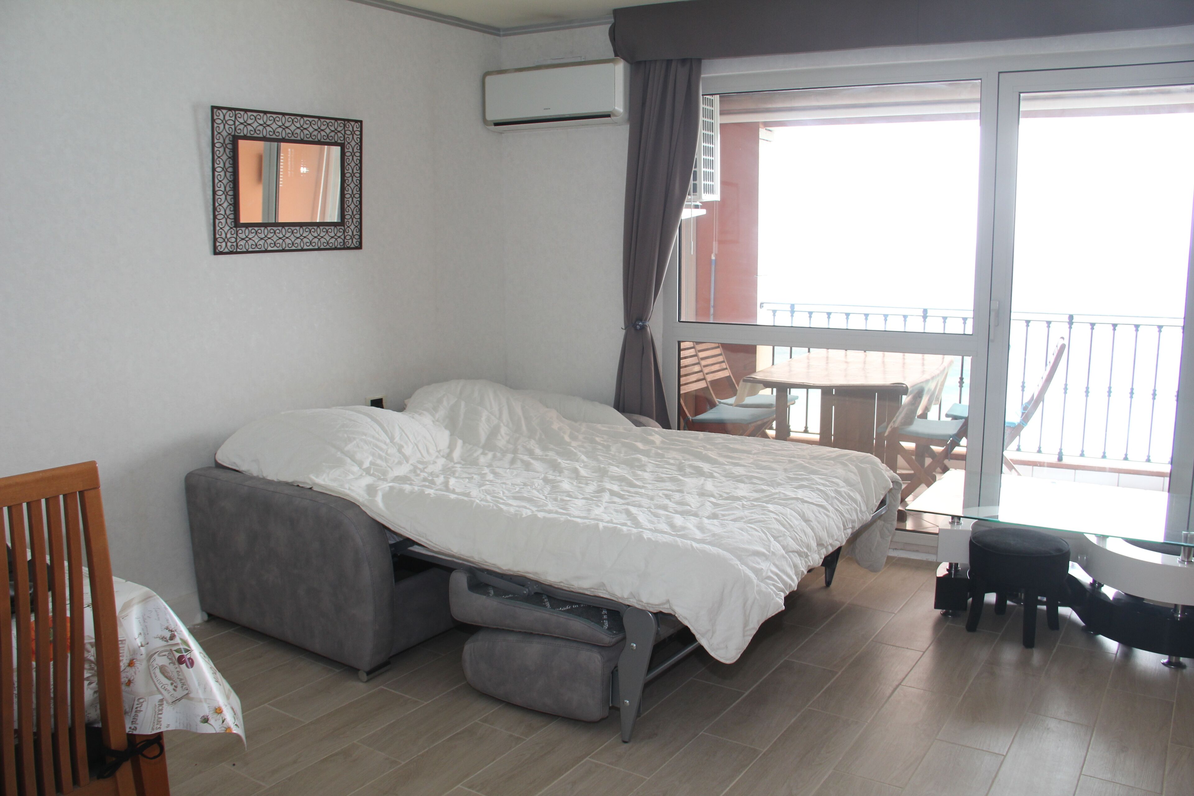 Ein Schlafzimmer mit Bett, Stuhl, kleinem Tisch und einem Balkon mit Tisch und Stühlen.