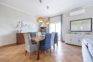 Een eetgedeelte met een houten tafel, stoelen en hanglampen.