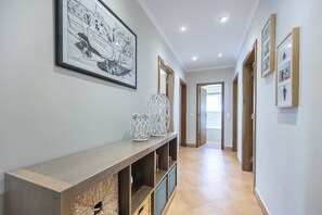 Un couloir avec une console en bois, des œuvres d’art encadrées et une vue sur une autre pièce.