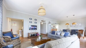 Un salón amplio con un sofá grande, un televisor y un comedor con sillas.