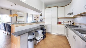 Una cocina moderna con armarios blancos, encimera de granito y horno empotrado.