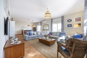A living room with a sofa, a coffee table, and a wicker chair. - CoolHouses Algarve Luz|Casa das Amendoeiras (Luz)