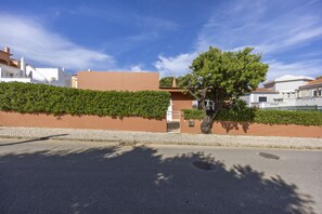 Une rue résidentielle bordée d’arbres, avec un trottoir, un ciel dégagé et un immeuble portant le numéro 33.