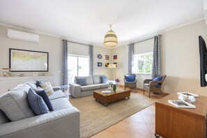 A spacious living room with a sofa, armchairs, a coffee table, and a television. - CoolHouses Algarve Luz|Casa das Amendoeiras (Luz)