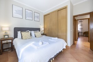 Une chambre d’hôtel avec un grand lit, une armoire en bois et des œuvres d’art encadrées accrochées au mur.