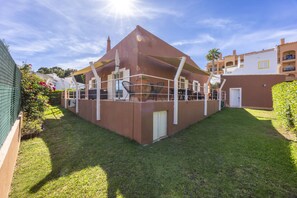 A covered outdoor seating area with tables and chairs, surrounded by a well-maintained lawn and a building with a flat roof. - CoolHouses Algarve Luz|Casa das Amendoeiras (Luz)