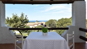 Un balcon avec une table et des chaises, offrant une vue panoramique sur les arbres et les bâtiments.